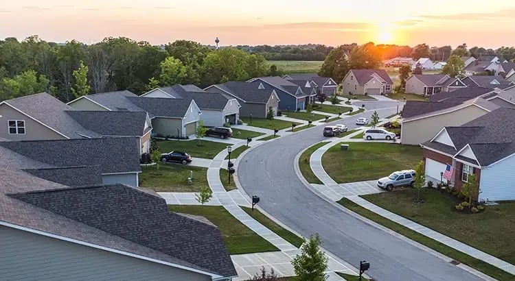 An aerial view of a suburban neighborhood with houses arranged along curved streets, showcasing a well-planned residential area.