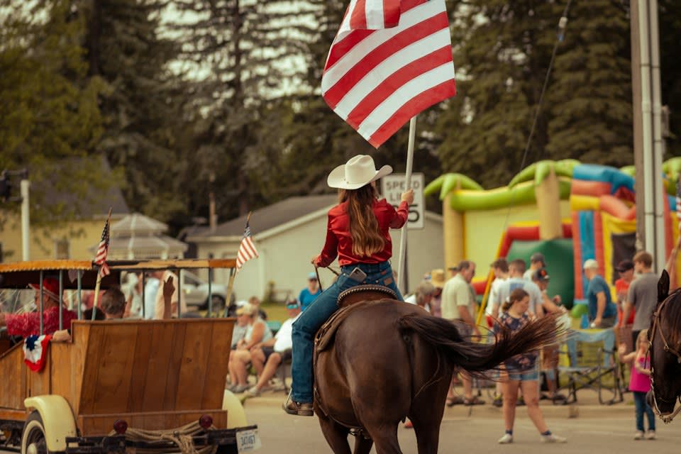 A Girl in a Cow Girl Suit Riding a Brown Horse