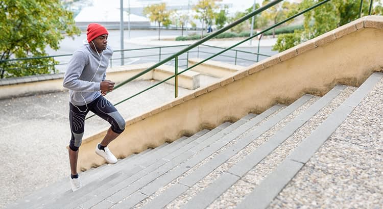 A person jogging up stairs – likely an exercise-related scene, with the individual in athletic clothing running up a set of concrete stairs.