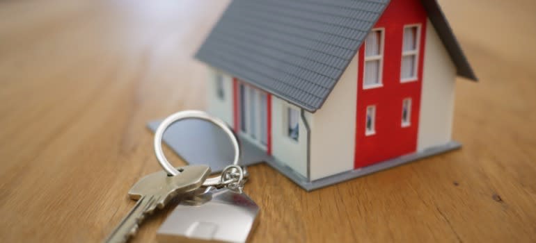 A miniature house next to a set of house keys
