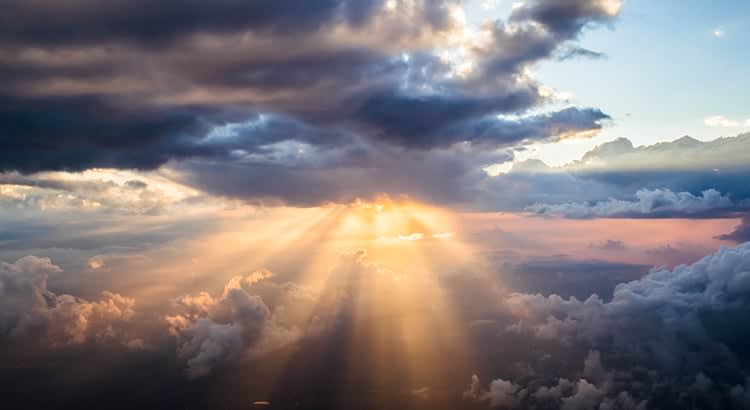 a dramatic and beautiful natural scene, featuring a break in the clouds where the sun's rays are streaming through.