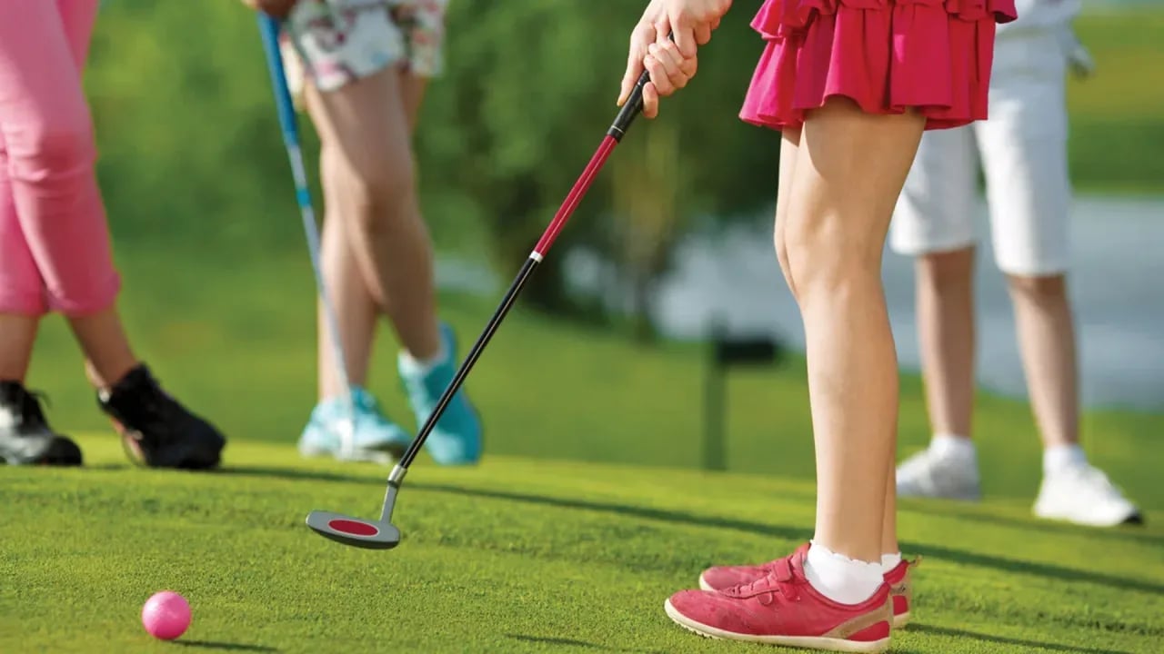 A woman playing golf with other people.