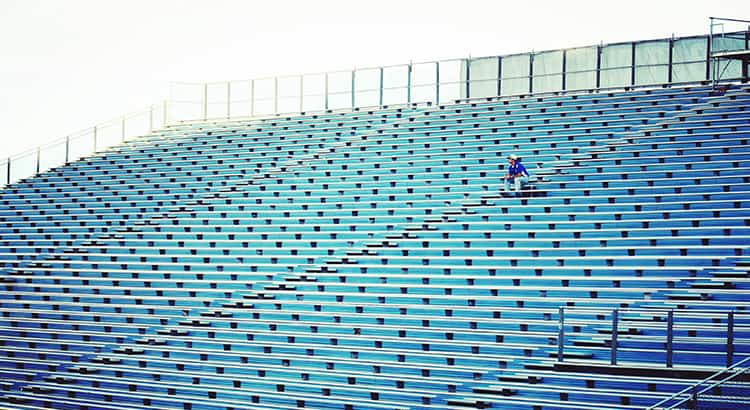 This wide-angle shot of empty bleachers, with a single person, gives a sense of solitude or contemplation, possibly relating to sports, events, or isolation.