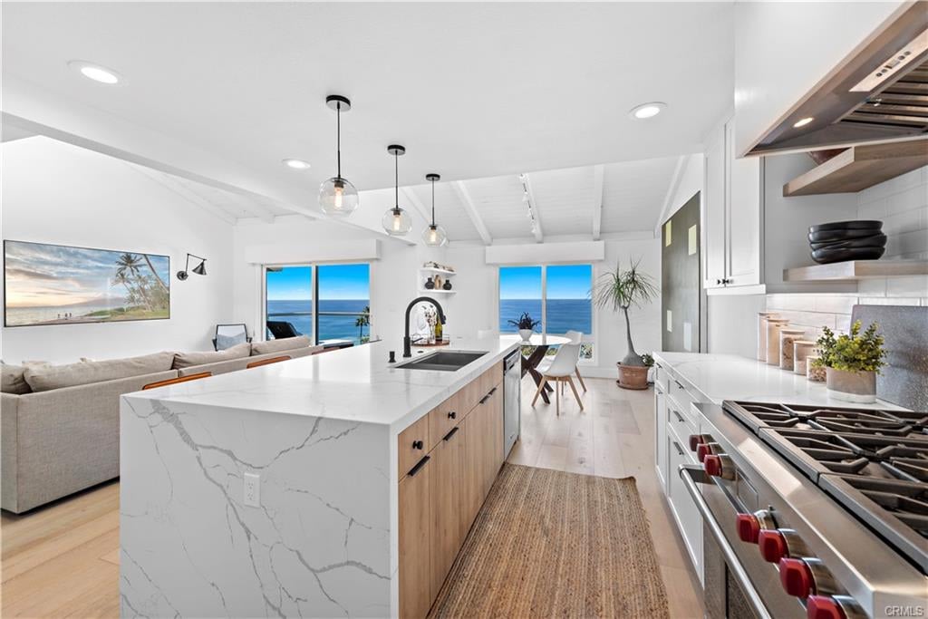 Ocean-view kitchen with a marble-veined island, white cabinetry, and adjoining living area.