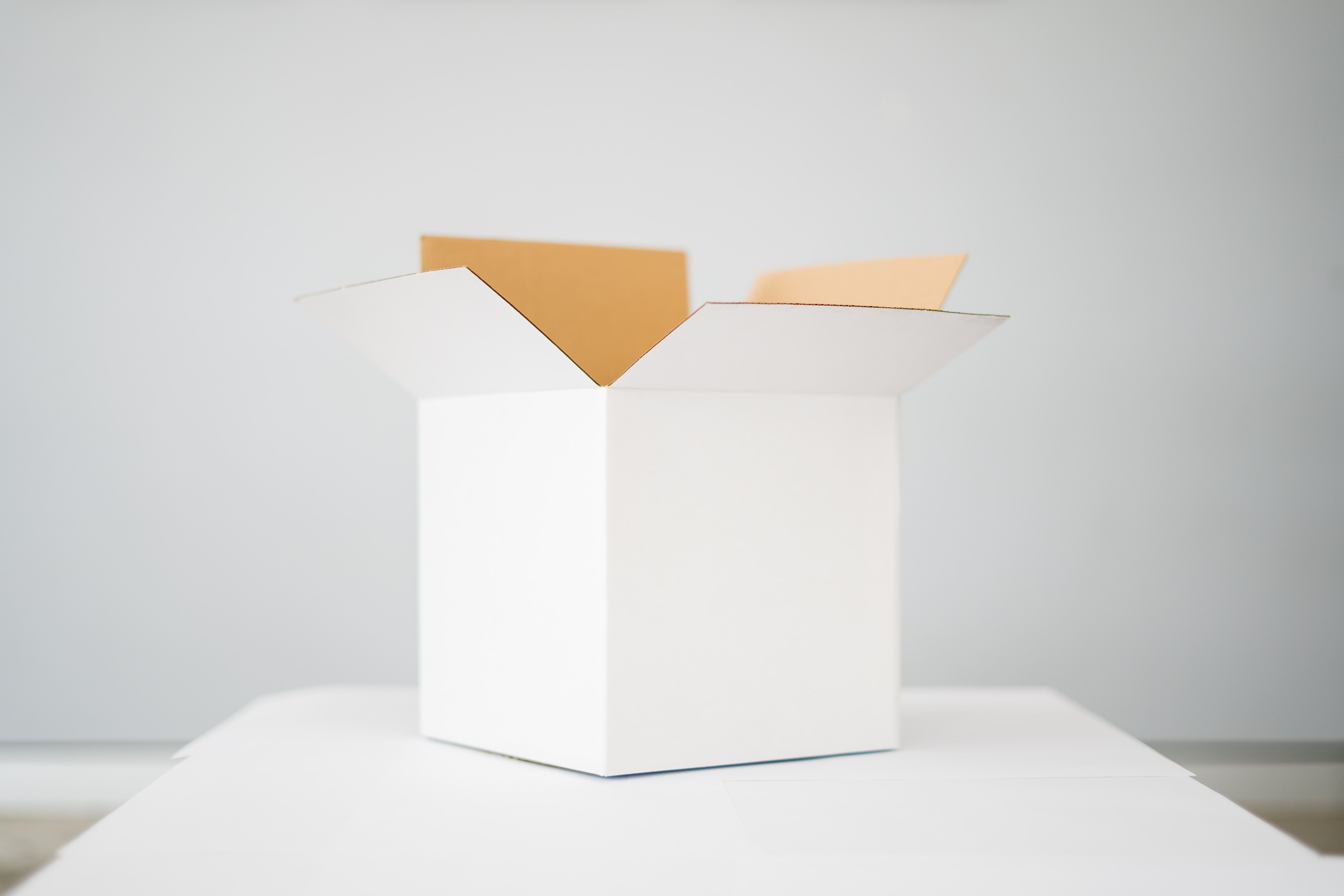 Open cardboard moving box with its flaps spread out on a white surface.