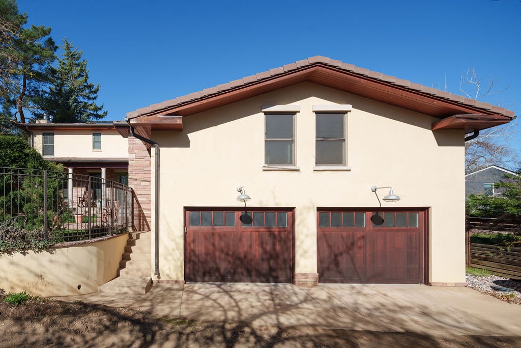 Detached garage with craftsman details, wooden doors, and curved staircase leading to main house