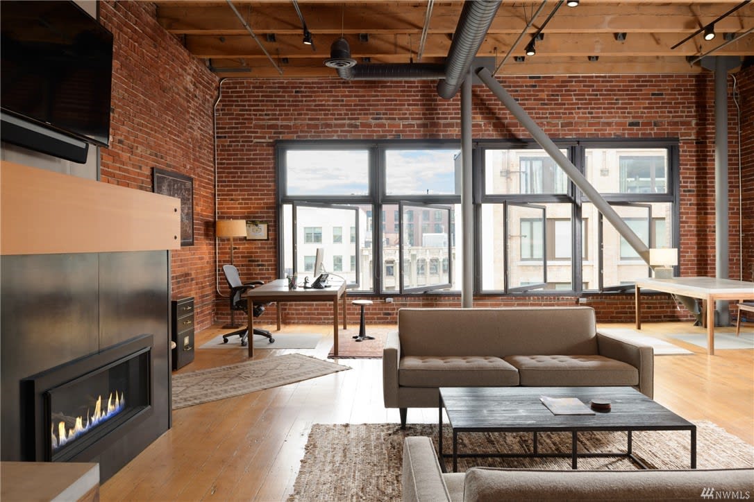 Sophisticated loft workspace blends with a relaxed living area, highlighting exposed brick and cityscape views.