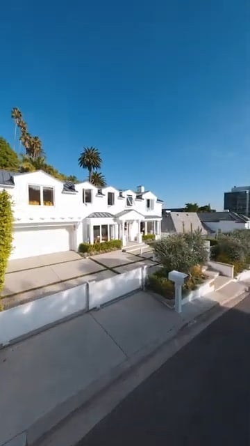 A large white house with a red tile roof and a driveway leading to a two-car garage. 