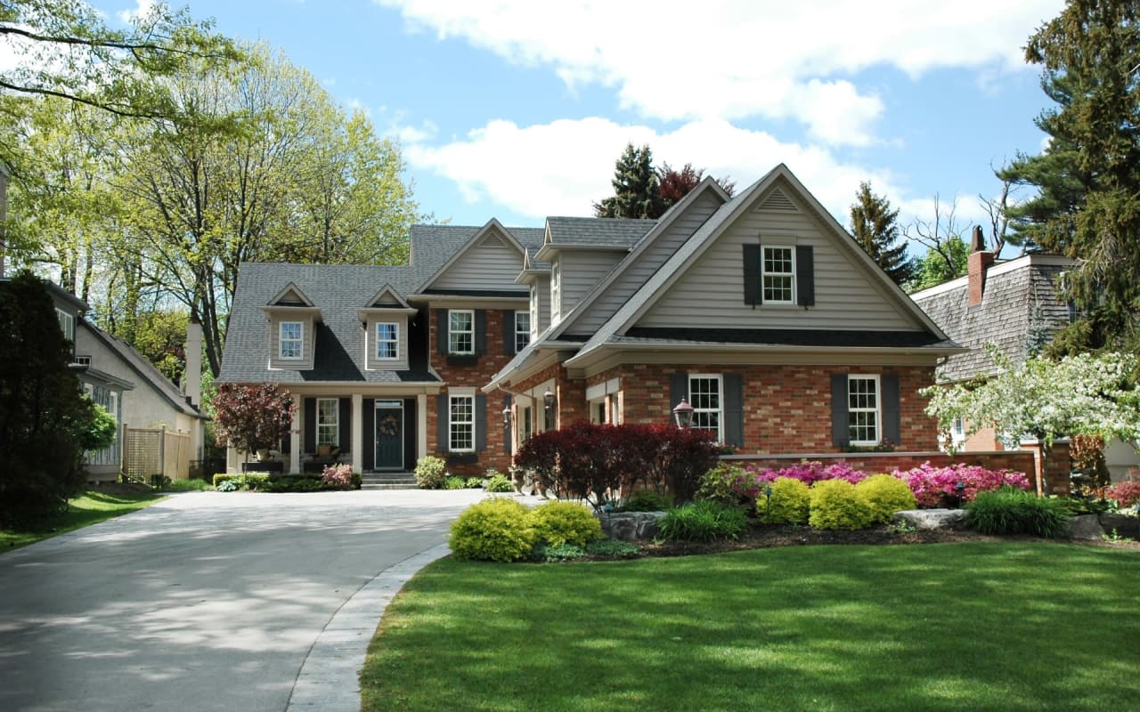 A beautiful house with a lush green lawn and a blue sky. The atmosphere is peaceful, and the mood is inviting and welcoming.