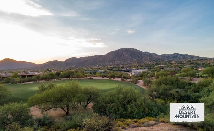 Desert golf course with lush fairways, green greens, and mountain views