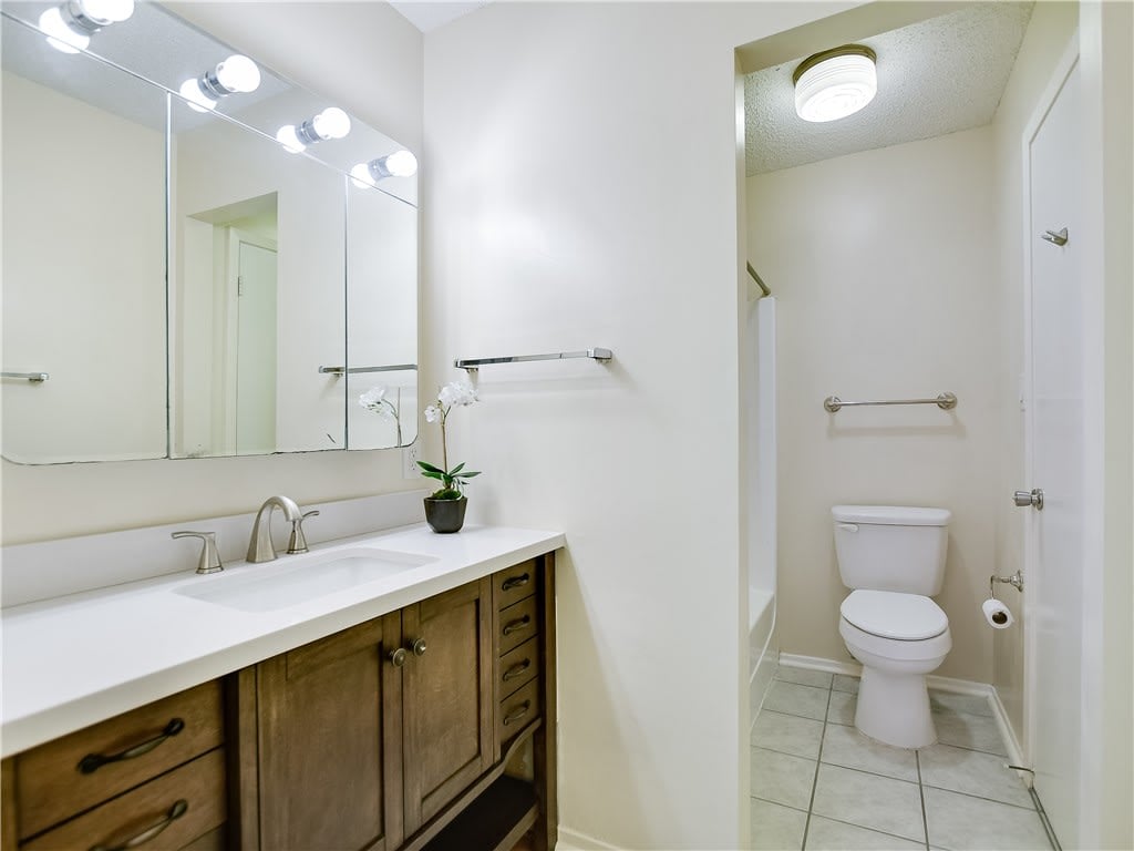 Bathroom with a dark wood vanity, large mirror, and separate toilet alcove.