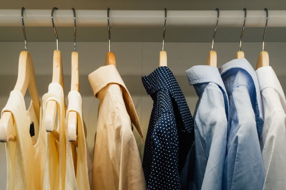Clothes hanging on wooden hangers in a closet.