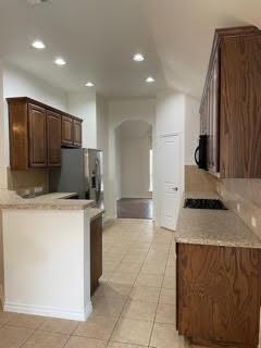 Kitchen with dark wood cabinets, granite counters, stainless appliances, and a tiled floor.
