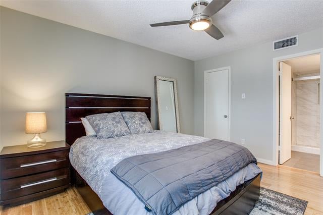 Bedroom with gray patterned bedding, dark wood furniture, a ceiling fan, and light wood flooring.