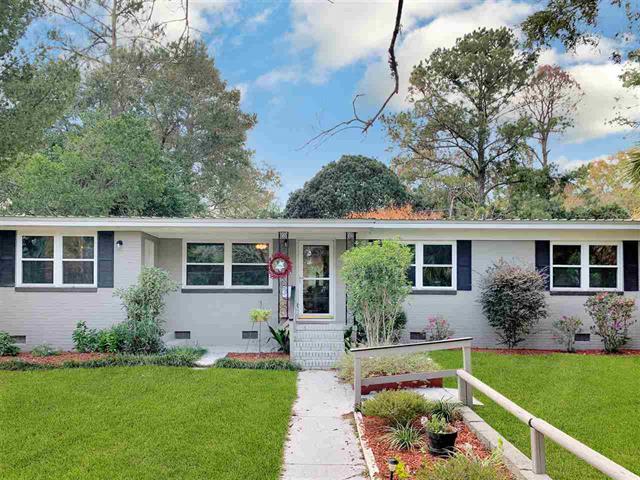 A single-story house in 1114 Beachum Dr with a light-colored exterior. The front yard is well-kept with green grass and various shrubs. A small porch with railings adds to the charm of the house.