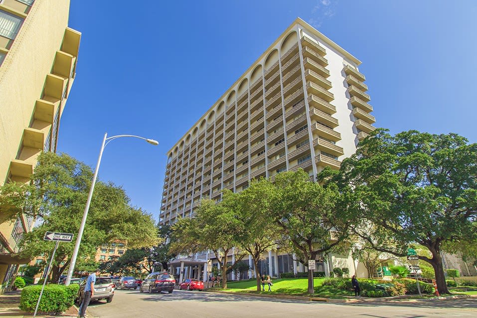 Residential buildings of the Cambridge Tower with concrete exterior finishes, balconies, and surrounded by trees.