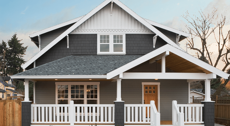 A house with a front porch, characterized by its craftsman-style architecture, featuring a gabled roof, white railings, and a spacious front yard.