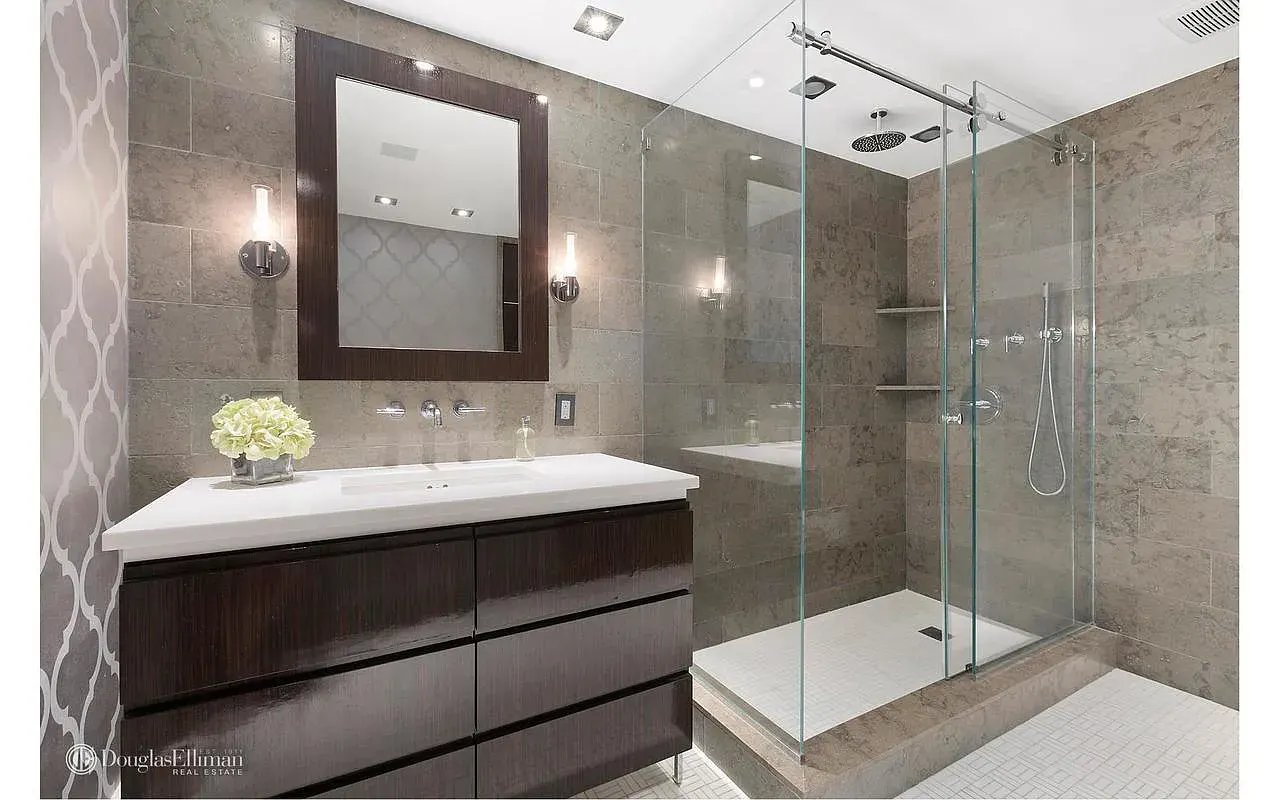 Modern bathroom with a dark wood vanity, large mirror, and glass-enclosed walk-in shower.