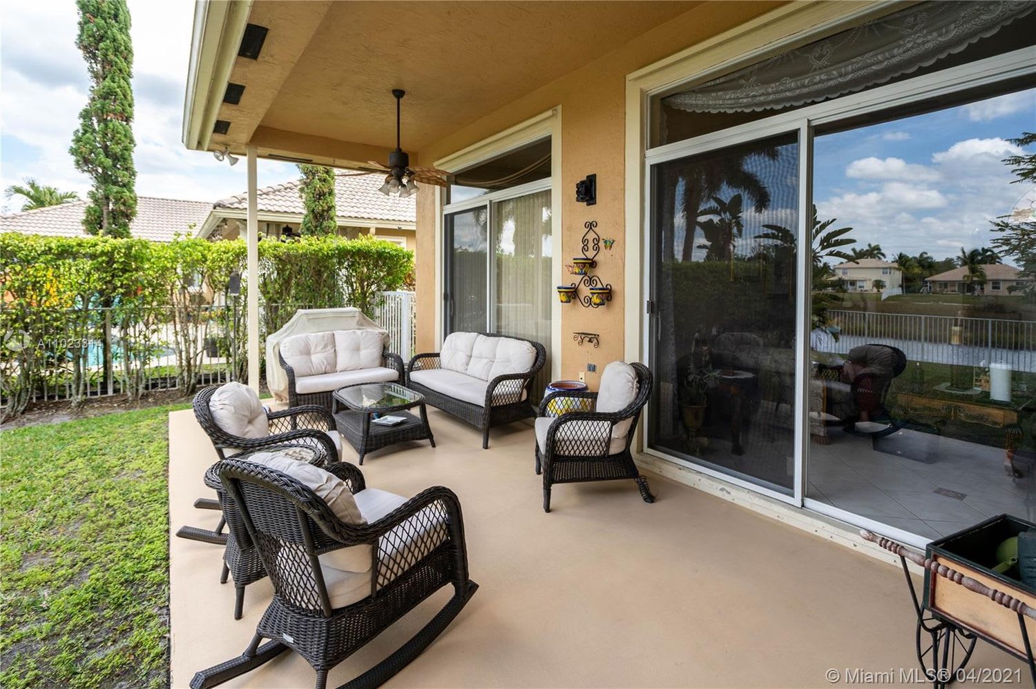 Covered patio with wicker seating and ceiling fan overlooks a canal.
