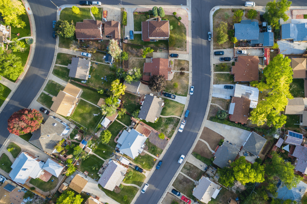 Aerial view of detached homes along neighborhood streets lined with mature trees.