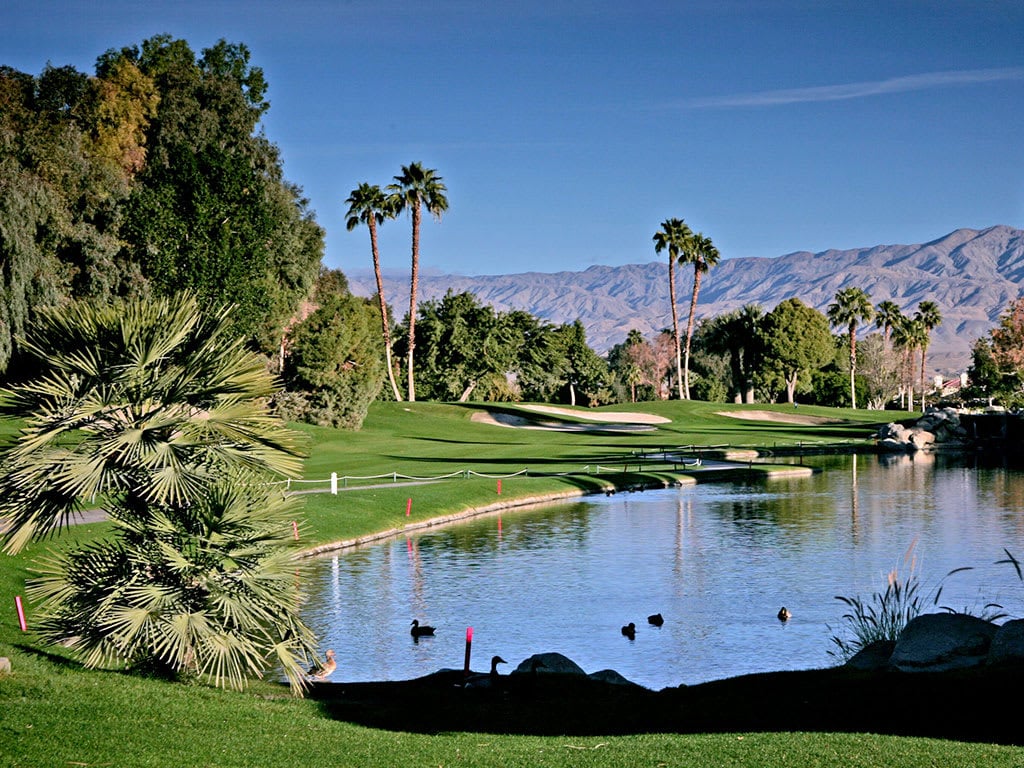 A golf course fairway with a pond in the foreground.