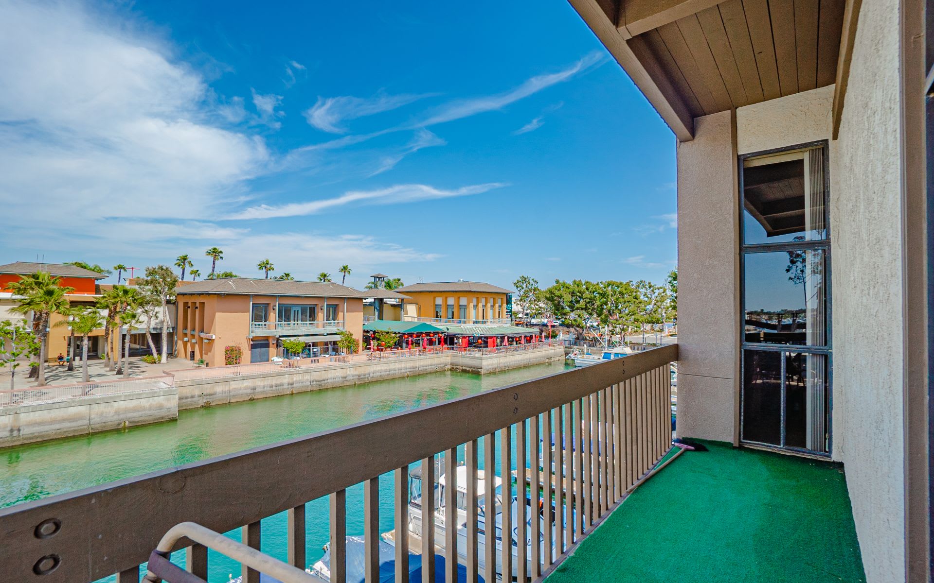 Condo balcony overlooking a canal, with boats and waterfront buildings across the water.
