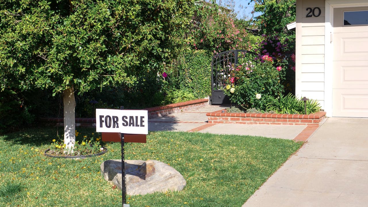 “For sale” sign on green grass lawn.