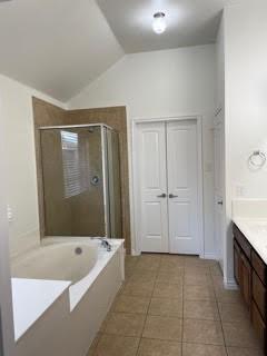 Bathroom with a built-in tub, glass shower enclosure, double closet doors, and beige tile floor.