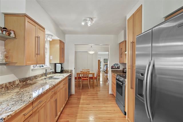 Kitchen with honey-colored cabinets, granite counters, stainless-steel refrigerator, and dining table beyond.