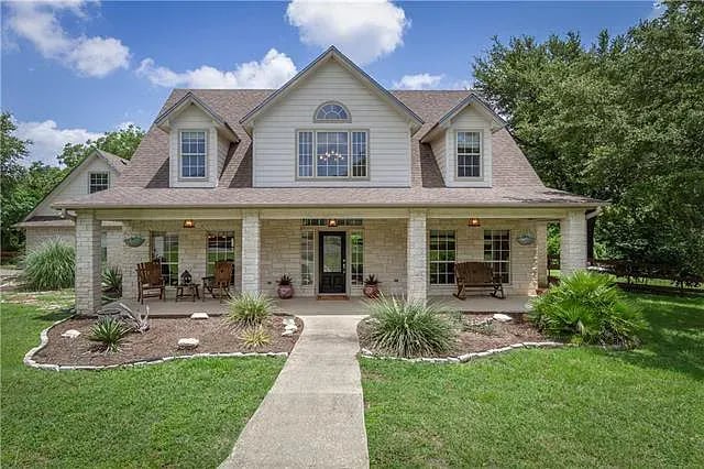 A large white house with a lush green yard.