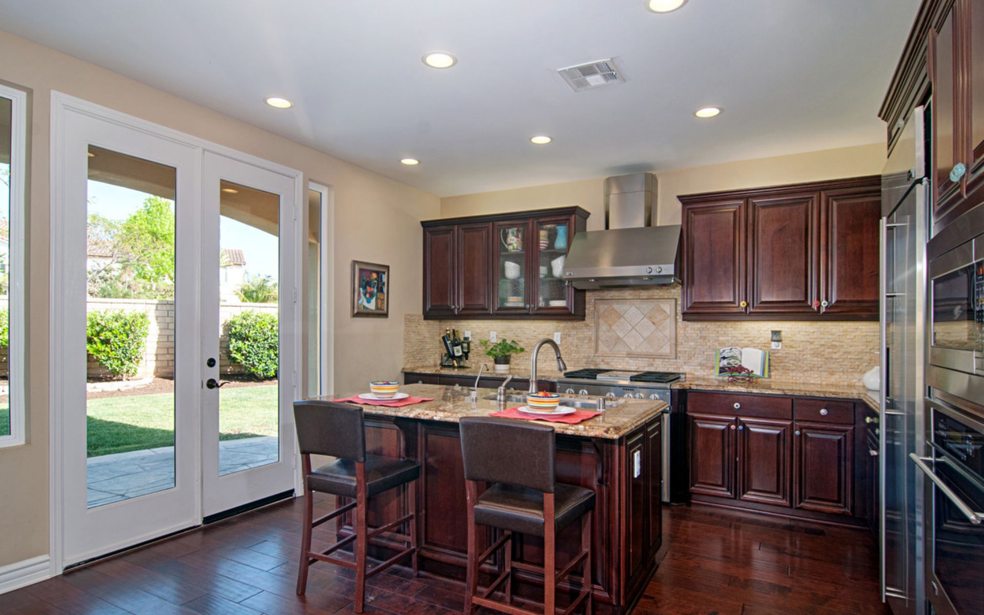 Kitchen with a granite island, dark wood cabinets, and glass doors opening to the backyard.