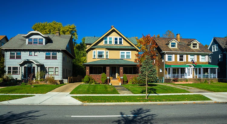 a row of charming, older-style houses on a sunny day in what appears to be a residential neighborhood. 