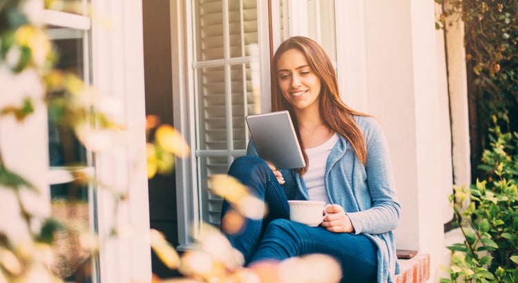 A woman sitting on a porch with a tablet, suggesting topics related to single women and homeownership.