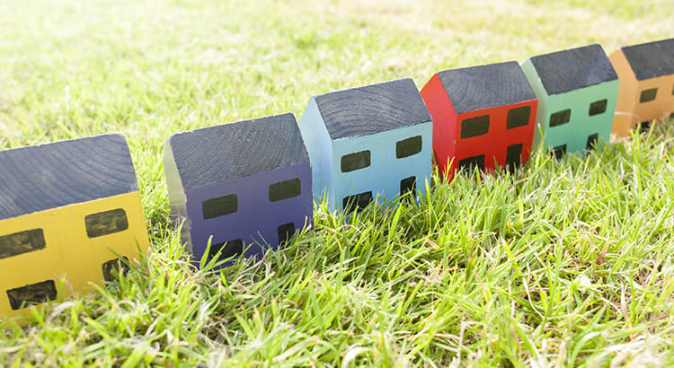 A small, colorful toy houses arranged on a grassy surface.