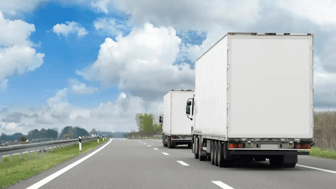 A large truck driving on a highway under a partly cloudy sky. The image suggests transportation, logistics, or moving.