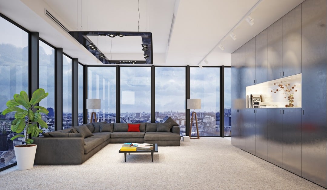 Modern living room with a gray sectional, floor-to-ceiling windows, and city skyline views.