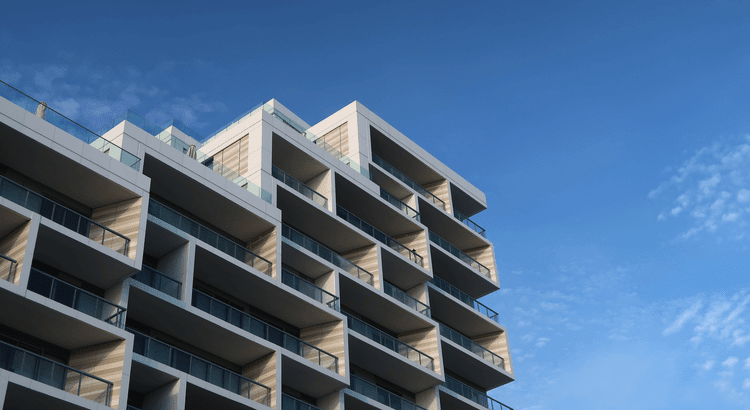 Modern apartment building featuring balconies against a clear blue sky backdrop.