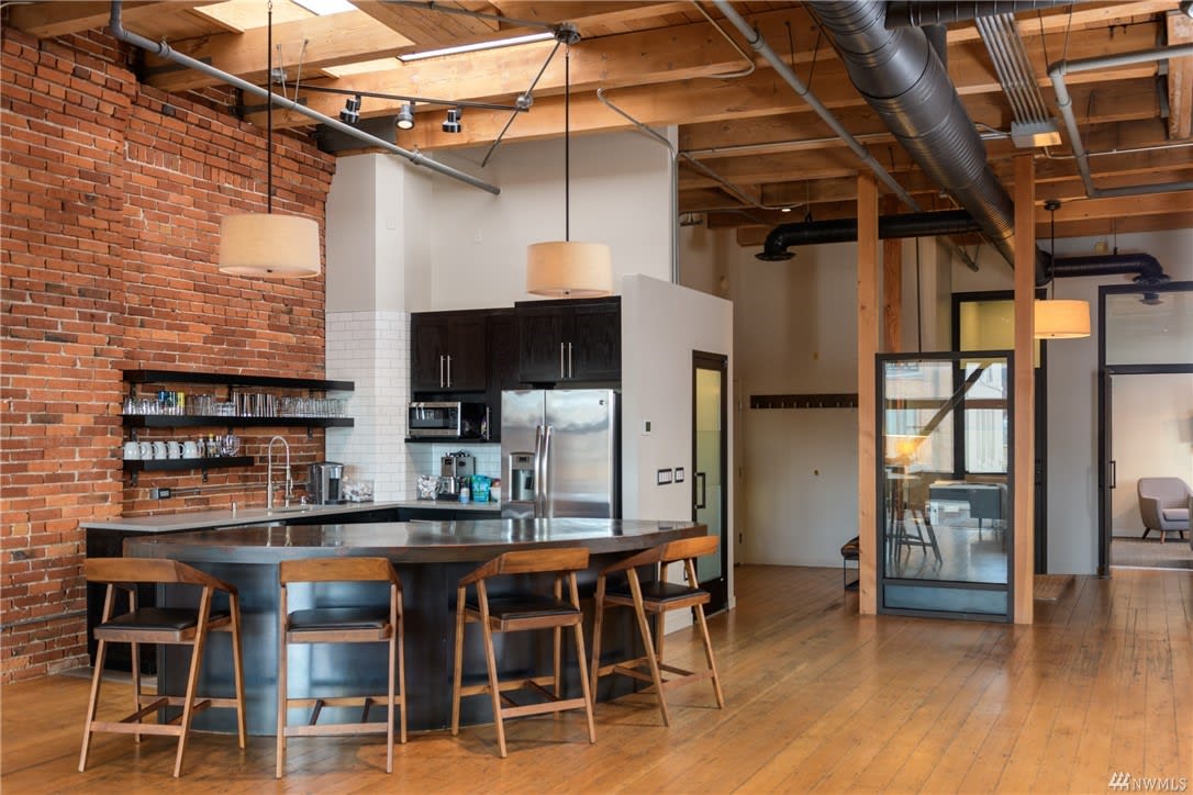 Warm, spacious loft with exposed brick, open-plan kitchen, and wooden beams.