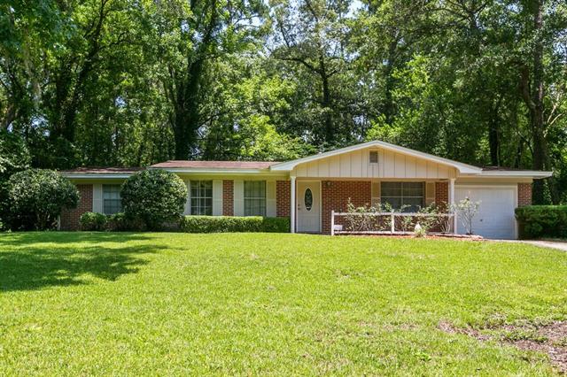 A single-story house in 1539 E Indian Head Dr with a simple design and a large, grassy front yard. The house has a small covered porch and is situated in a wooded area.