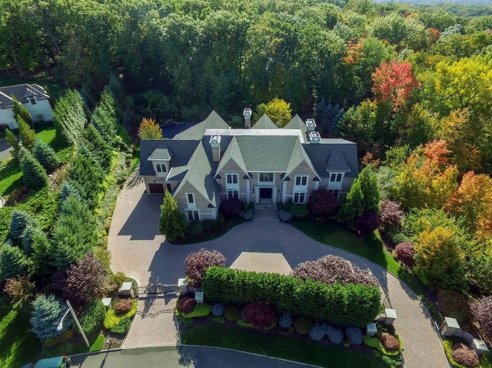 An aerial view of a secluded mansion nestled amidst a lush green forest