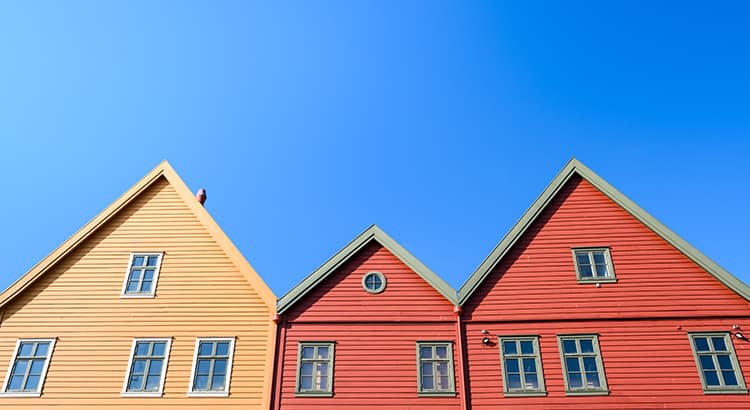 a bright, minimalistic view of three colorful houses against a clear, blue sky. 