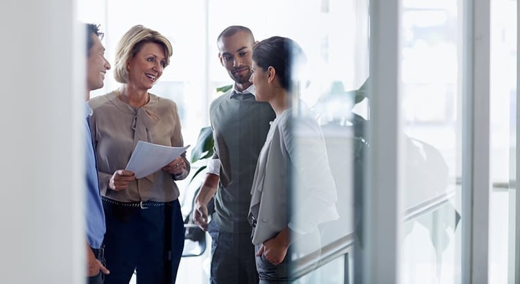 A group of people having a discussion in a professional setting. The photo suggests themes of teamwork, collaboration, and business interactions.