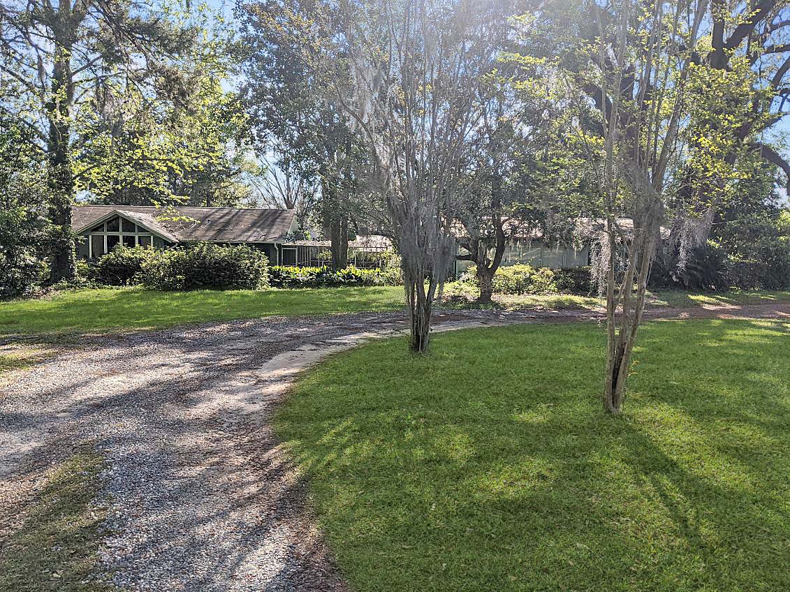 A ground-level view of a house with a well-maintained lawn and trees, indicating a property that has recently been sold.