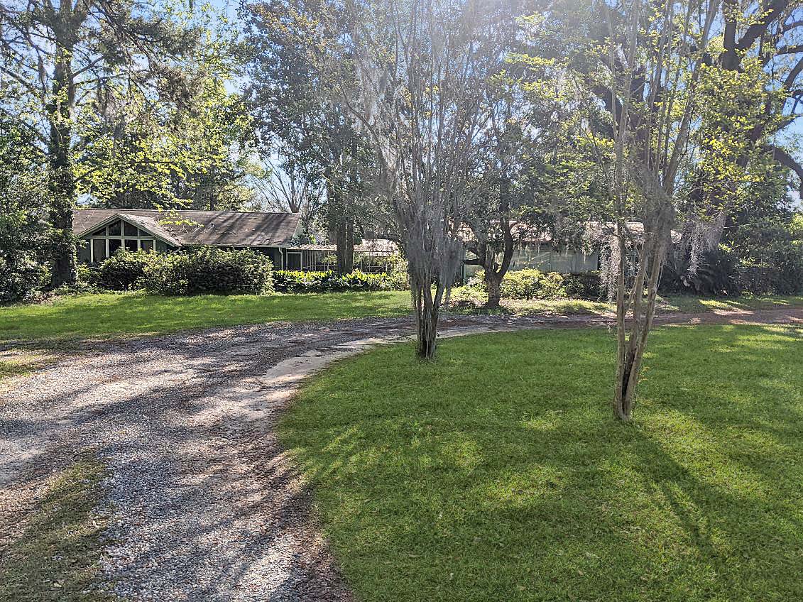 A ground-level view of a house with a well-maintained lawn and trees, indicating a property that has recently been sold.