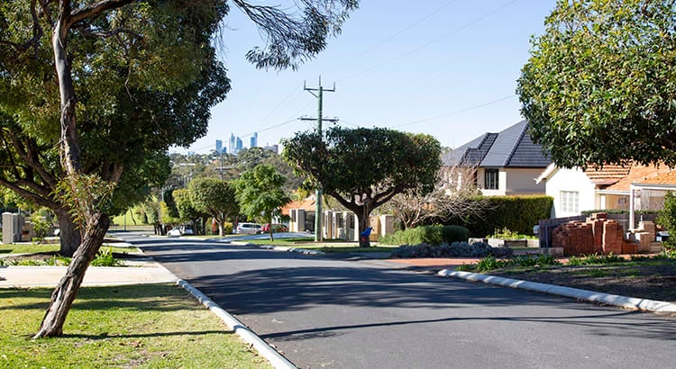 A picturesque suburban street lined with trees and well-maintained houses. The photo highlights the tranquility and charm of a residential neighborhood.