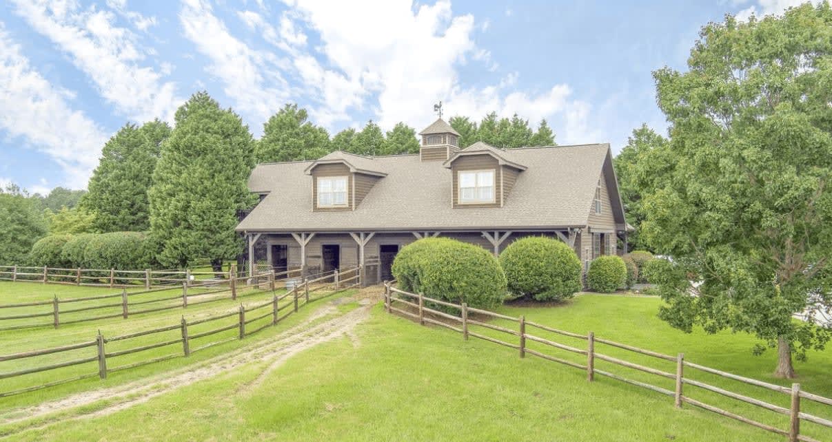 Rustic luxury barn-style home with spacious green lawns and fenced paddocks, offering a tranquil rural estate living.