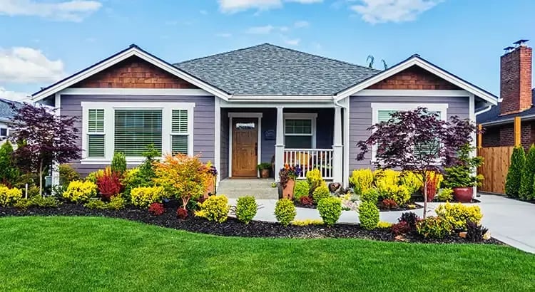 A charming suburban house with a well-manicured lawn and garden. The house has a classic design with a welcoming front porch.