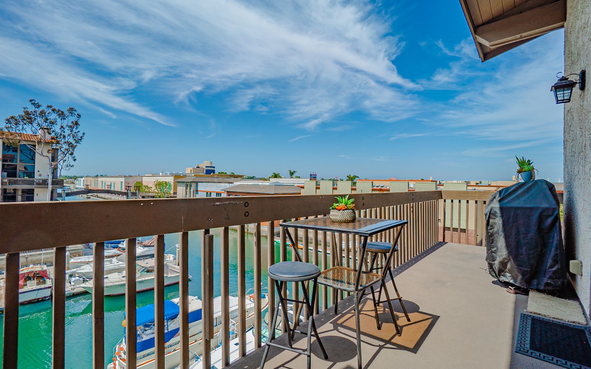 Balcony overlooking marina boats, furnished with a small table and chairs.