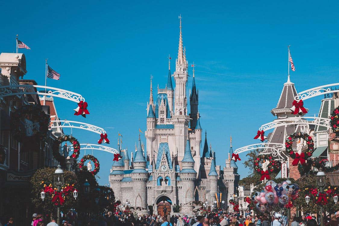 A winter scene at Disney World, featuring snow-covered attractions and festive decorations under a clear blue sky.