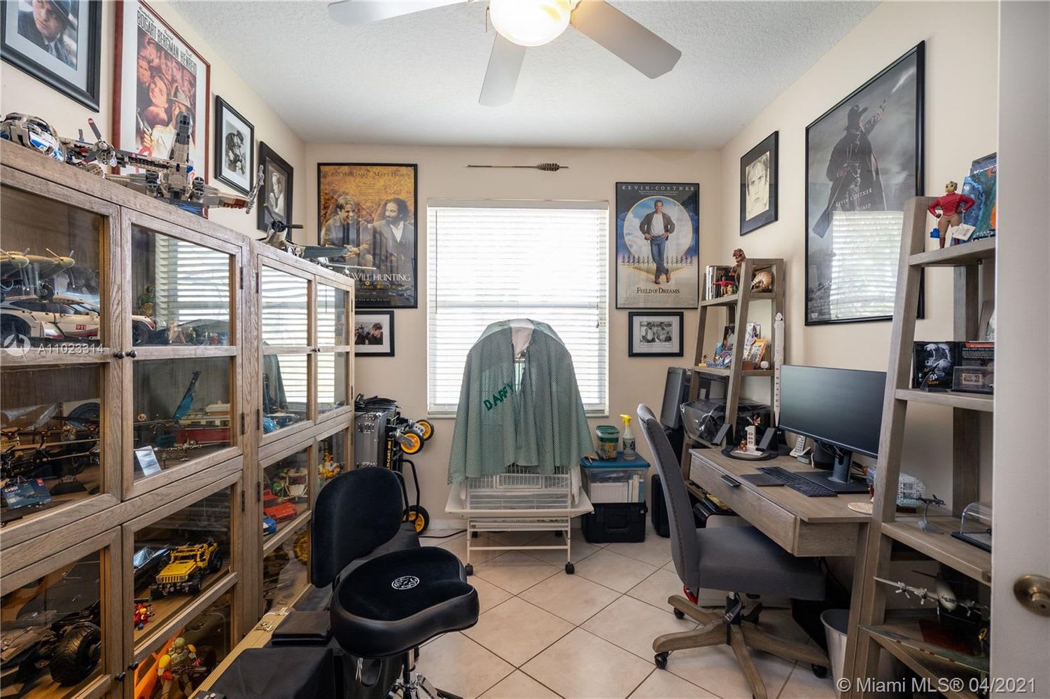 Home office with a computer desk and glass display cabinets filled with collectibles and model vehicles.